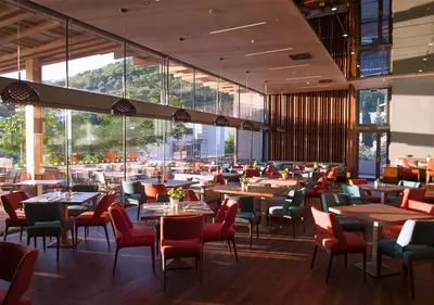 a dining room with tables and chairs and windows at Maestral Resort & Casino in Budva
