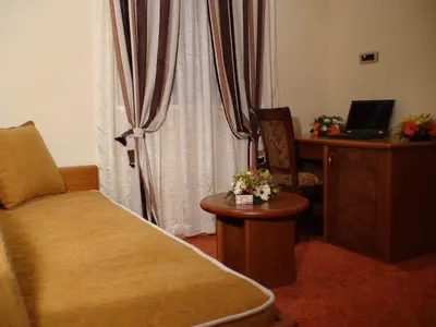 a room with a bed and a desk with a laptop at Mali Hotel BaMBiS in Podgorica
