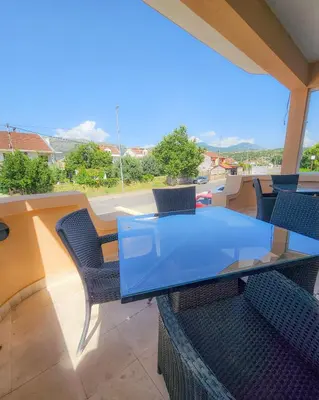 a glass table and chairs on a balcony at Mali Hotel BaMBiS in Podgorica