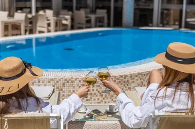two women sitting at a table with glasses of wine at Apartments Del Mar in Petrovac na Moru