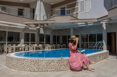 a woman sitting in front of a swimming pool at Apartments Del Mar in Petrovac na Moru