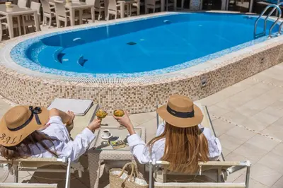 two people sitting in chairs next to a swimming pool at Apartments Del Mar in Petrovac na Moru
