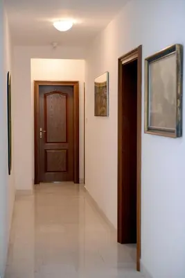 a hallway with a door and paintings on the wall at Hotel Sanja former Oliva in Budva