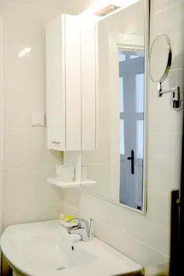 a white bathroom with a sink and a mirror at Hotel Sanja former Oliva in Budva