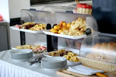 a buffet with several trays of bread and pastries at Hotel Sanja former Oliva in Budva