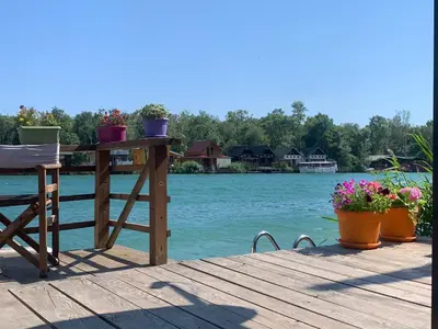 a table and chairs on a dock with the water at Lola - Ada Bojana River House in Ulcinj
