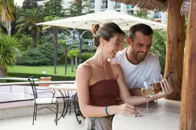 a man and a woman sitting at a table with wine glasses at Iberostar Waves Bellevue All Inclusive in Budva