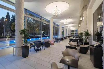 a lobby with tables and chairs and a pool at Hilton Podgorica Crna Gora in Podgorica