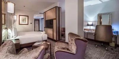 a hotel room with a bed and a desk and chairs at Hilton Podgorica Crna Gora in Podgorica