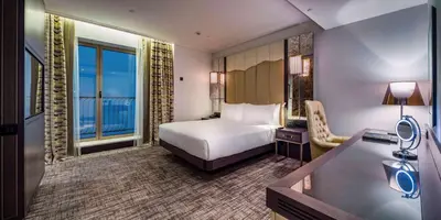 a hotel room with a bed and a desk and a room with a window at Hilton Podgorica Crna Gora in Podgorica
