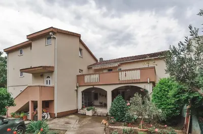 a large house with a car parked in the driveway at Markoni Apartments in Budva
