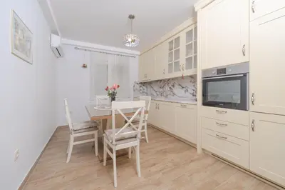 a kitchen with white cabinets and a table and chairs at Markoni Apartments in Budva