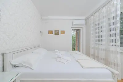 a white bedroom with a bed and a window at Markoni Apartments in Budva