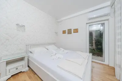a white bedroom with a bed and a window at Markoni Apartments in Budva