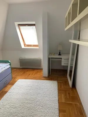 a bedroom with a bed and a desk and a window at Stan u strogom centru grada in Podgorica
