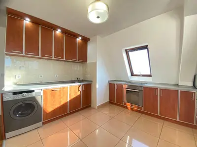 a kitchen with wooden cabinets and a washer and dryer at Stan u strogom centru grada in Podgorica
