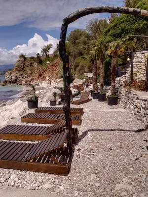 a group of wooden benches sitting on a rocky beach at Villa Golda, The whole house Biker Friendly in Rijeka Reževići