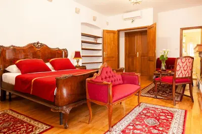 a bedroom with a red bed and two chairs at Casa Antica Druško in Kotor