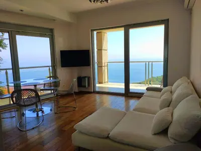 a living room with a couch and a table and windows at Nature Escape Infinity Pool and Amazing Sea View in Budva