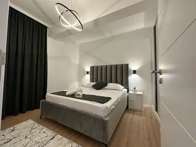 a bedroom with a large bed and a chandelier at Swiss Apartments 1 in Ulcinj