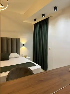 a bedroom with a bed and a green curtain at Swiss Apartments 1 in Ulcinj