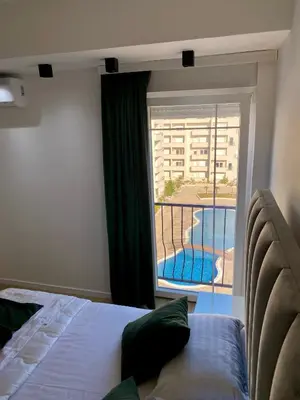 a bedroom with a bed and a balcony with a swimming pool at Swiss Apartments 1 in Ulcinj