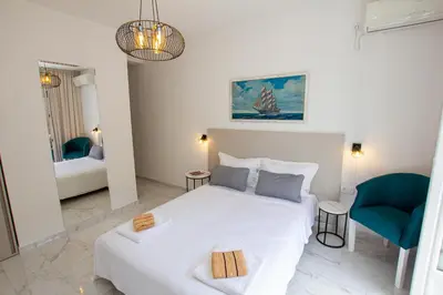 a bedroom with a white bed and a blue chair at Marco Polo in Petrovac na Moru