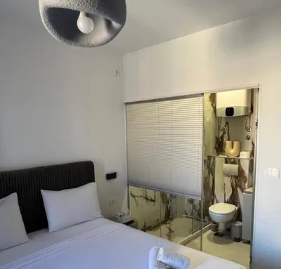 a bedroom with a bed and a bathroom with a toilet at Marco Polo in Petrovac na Moru