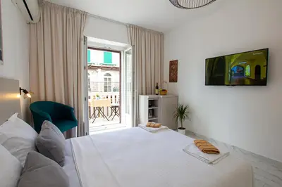 a white bedroom with a bed and a window at Marco Polo in Petrovac na Moru