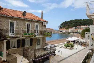 a building with a balcony next to a body of water at Marco Polo in Petrovac na Moru