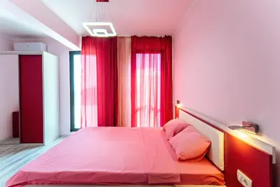 a bedroom with a pink bed and red curtains at Budva Gate in Budva