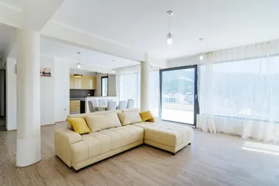 a living room with a white couch and a large window at Budva Gate in Budva