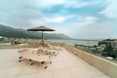 a balcony with two chairs and an umbrella at Budva Gate in Budva