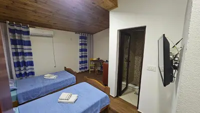 a room with two beds and a table and a mirror at Old Town - Guest House in Stari Bar