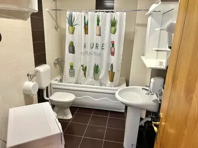 a bathroom with a toilet and a shower curtain with plants on it at Romantica Apartments in Ulcinj