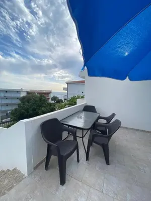 a table and chairs on a balcony with an umbrella at Guest House in Utjeha in Utjeha