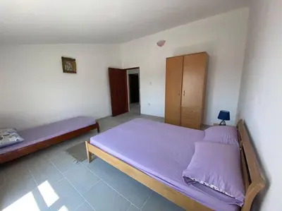 a bedroom with two beds with purple sheets at Guest House in Utjeha in Utjeha