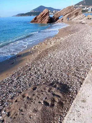 a rocky beach with footprints in the sand and water at Perovic 23 in Rafailovici