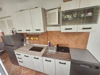 a kitchen with white cabinets and a sink and a refrigerator at Perovic 23 in Rafailovici