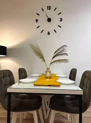 a dining room table with a clock on the wall at Swiss Apartments 2 in Ulcinj