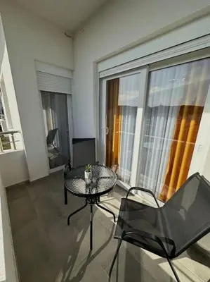 a table and chairs in a room with a large window at Swiss Apartments 2 in Ulcinj