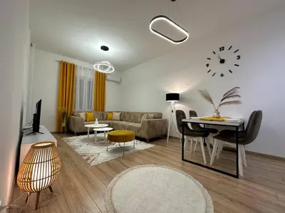 a living room with a couch and a table and a clock at Swiss Apartments 2 in Ulcinj