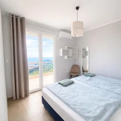 a white bedroom with a bed and a large window at Golden Horizon Villas in Budva
