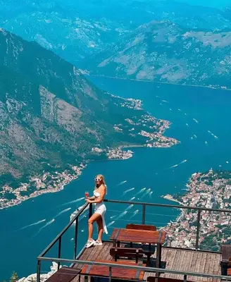 a woman sitting on the edge of a balcony overlooking a lake at Golden Horizon Villas in Budva