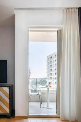 a sliding glass door leading to a balcony with a chair at Adriatic Dream Apartment Becici in Budva