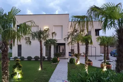 a large white house with palm trees in the yard at Villa „Taki“ Podgorica in Podgorica