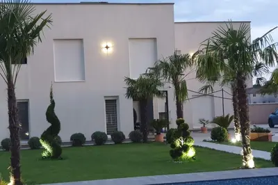 a white house with palm trees in front of it at Villa „Taki“ Podgorica in Podgorica