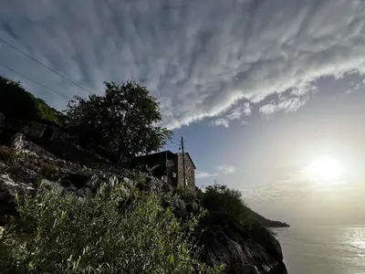a building on the side of a hill next to the water at Lakeview Apartments Jolicic in Virpazar