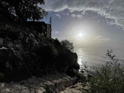 a sun setting over the water next to a rocky shore at Lakeview Apartments Jolicic in Virpazar