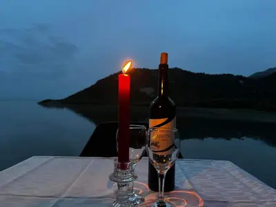 a bottle of wine and a candle on a table at Lakeview Apartments Jolicic in Virpazar